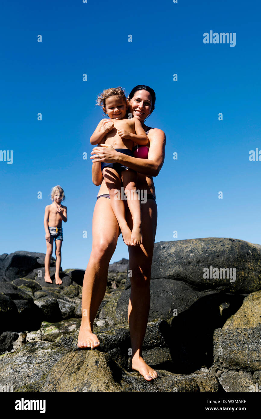Woman with her sons on rocks at beach Stock Photo