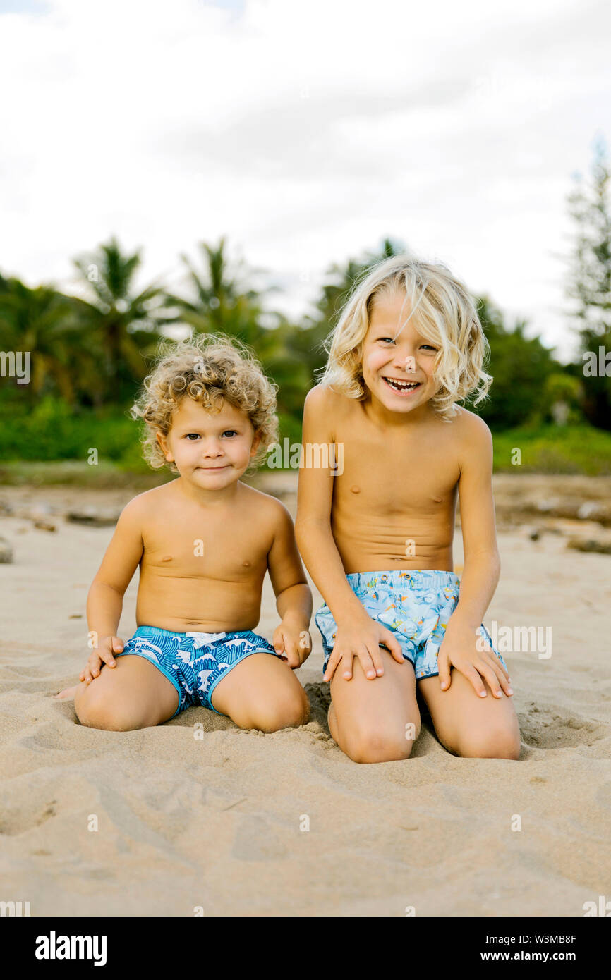 Brothers kneeling on beach Stock Photo