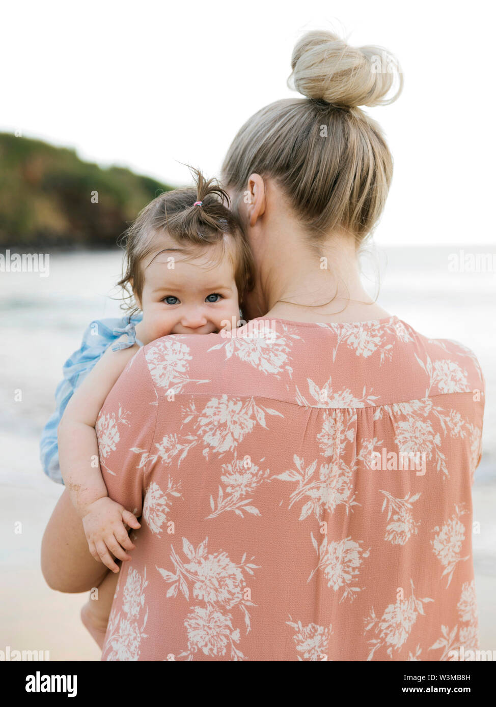 Woman holding baby daughter on beach Stock Photo