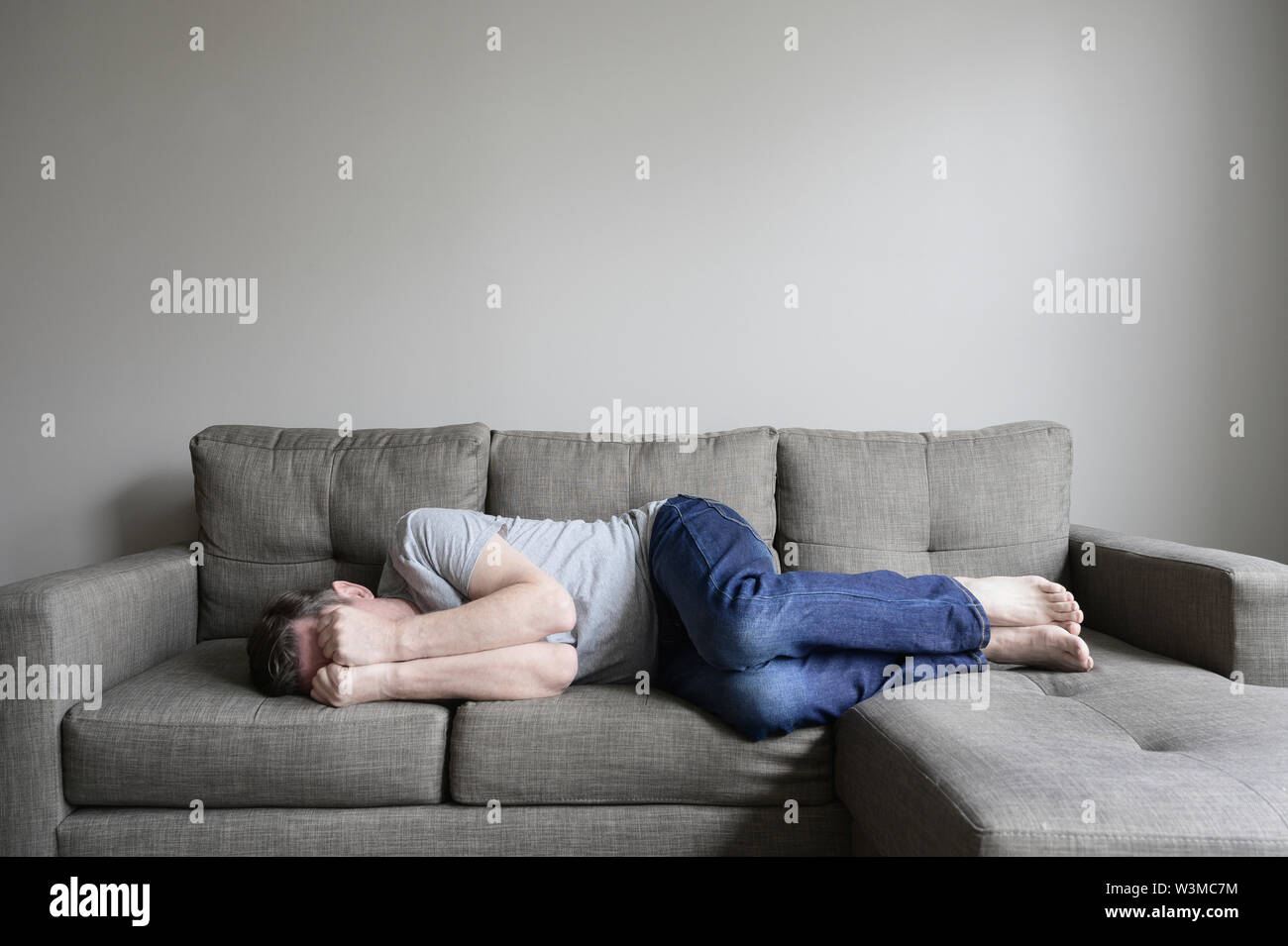 Depressed mature man lying on sofa Stock Photo