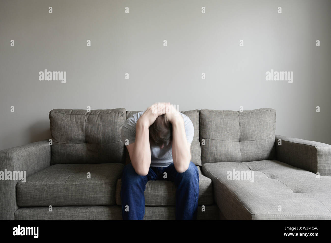 Depressed mature man sitting on couch Stock Photo