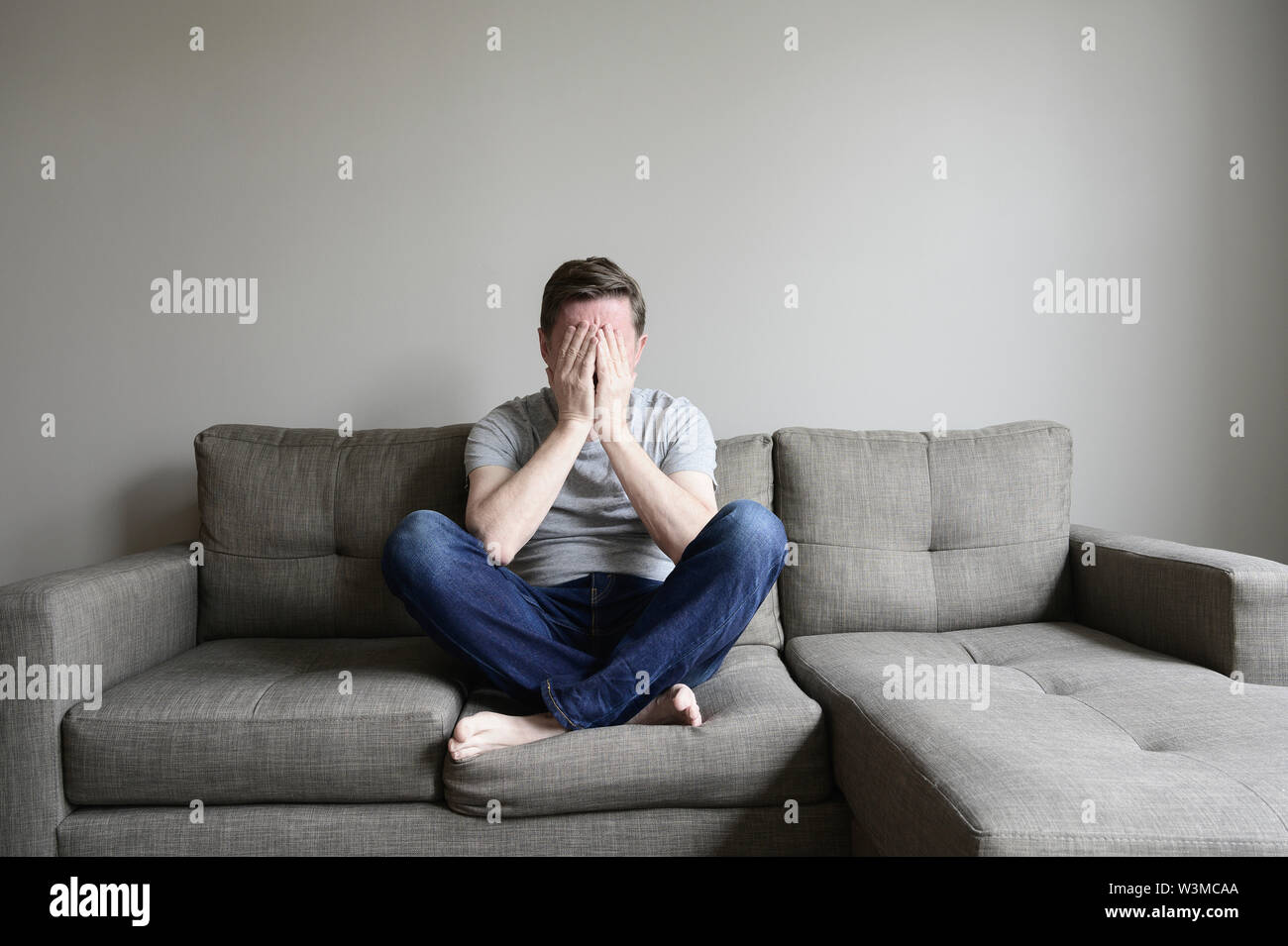 Depressed mature man sitting on couch Stock Photo