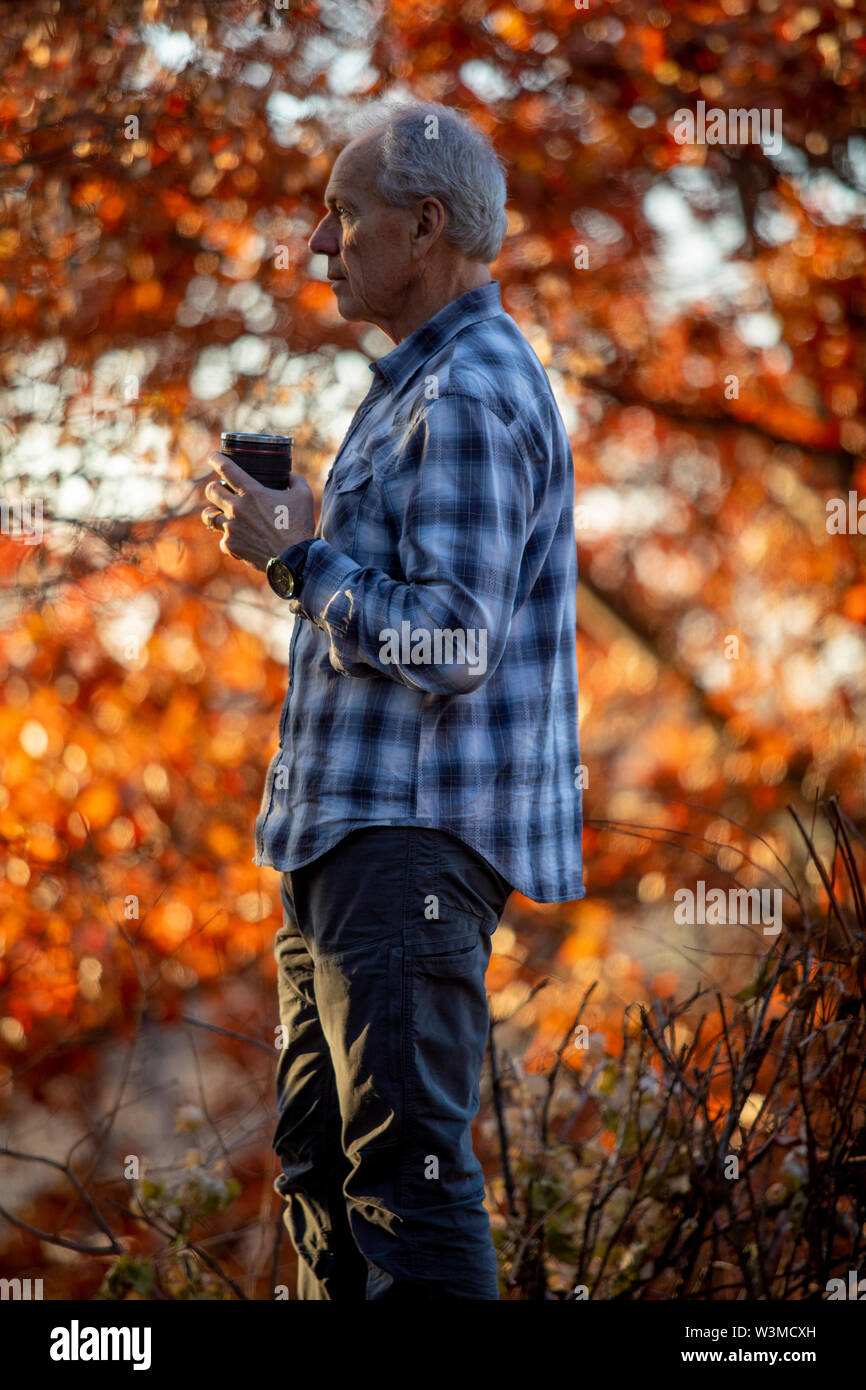 Man holding coffee cup by autumn trees Stock Photo