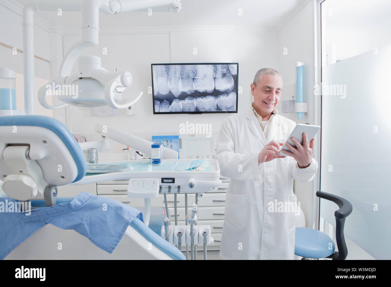 Dentist using digital tablet in dentist's surgery Stock Photo