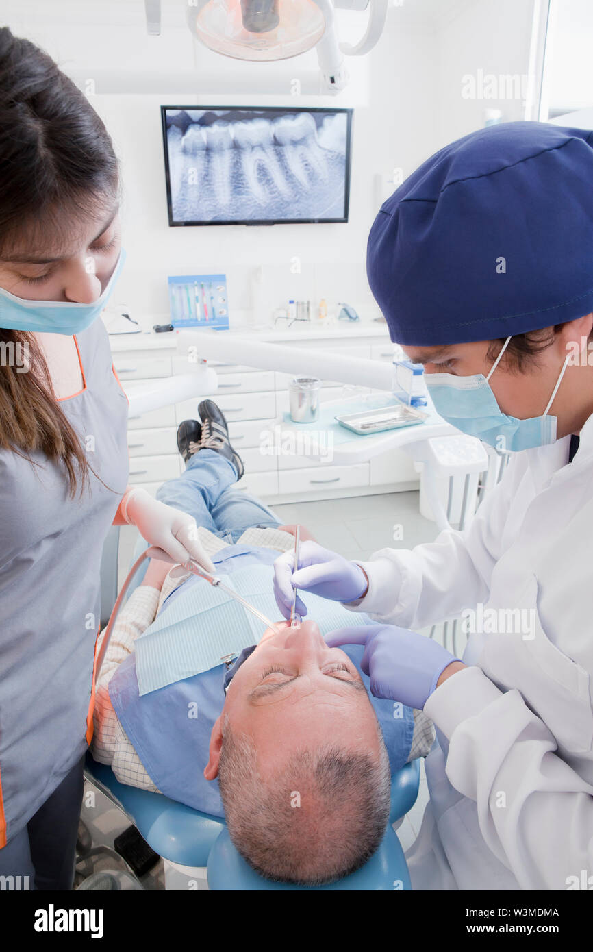 Dentist and hygienist cleaning patient's teeth Stock Photo