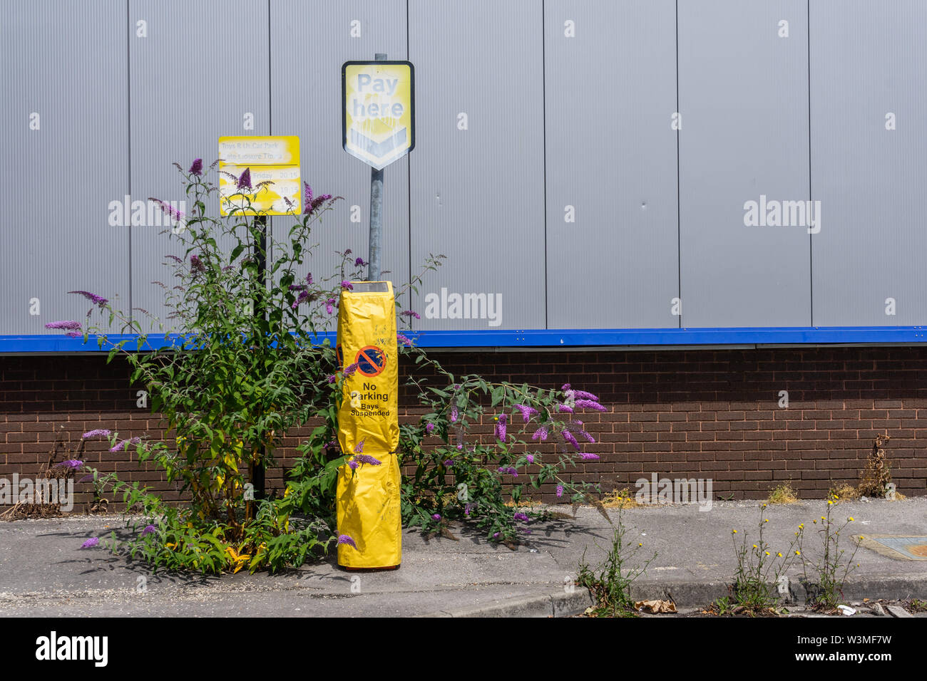 Disused and overgrown parking sign and pay machine on suspended parking bays in Southampton, England, UK Stock Photo