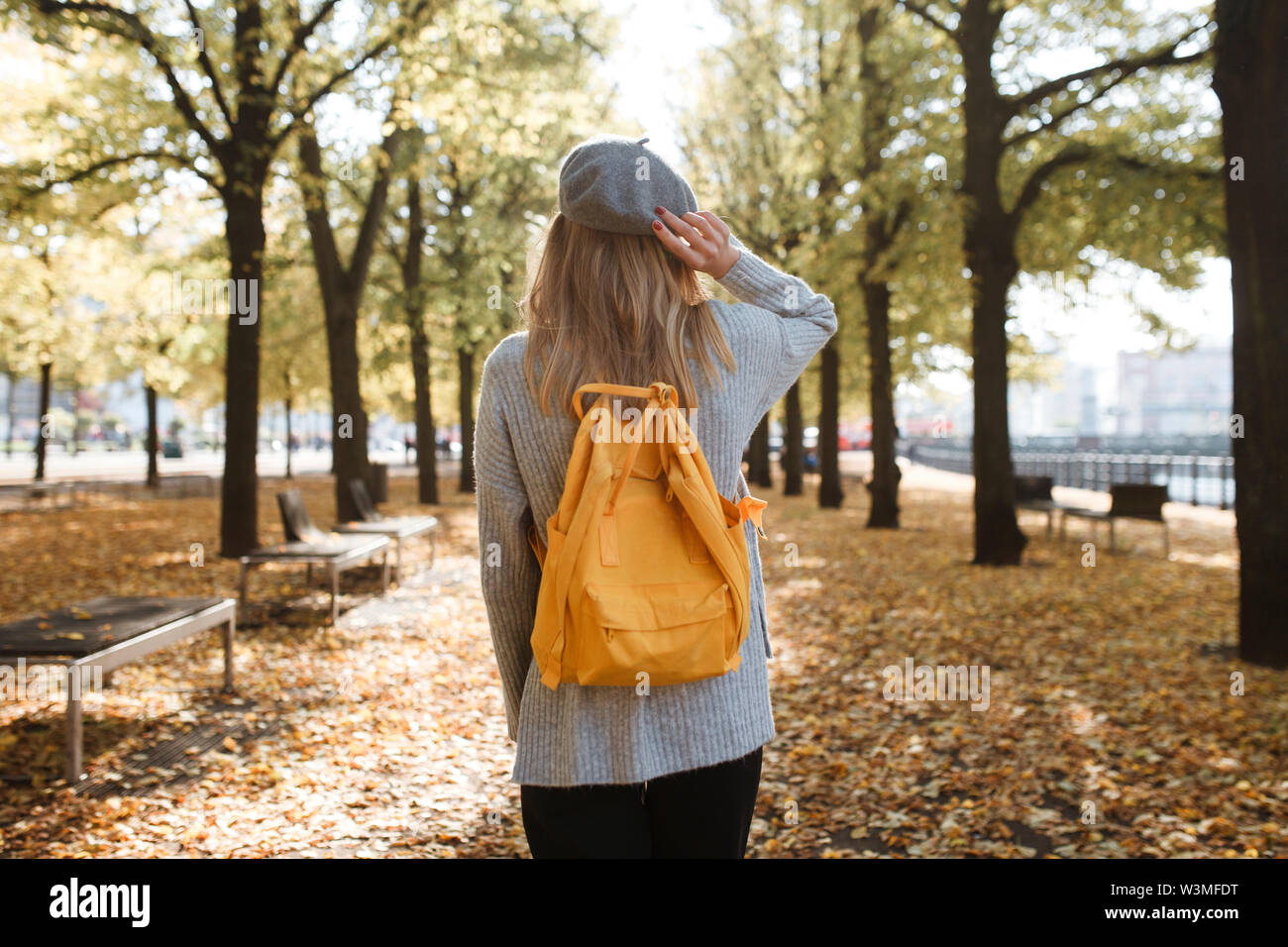 Young woman with yellow backpack in park in Berlin, Germany Stock Photo