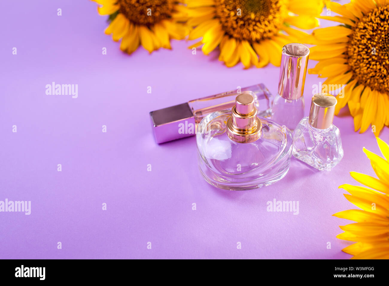 Bottles of perfume with sunflowers on purple background. Organic