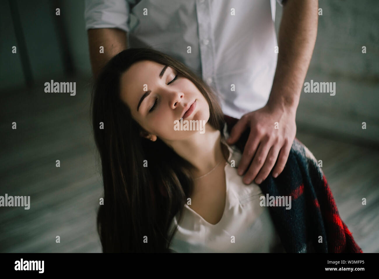 Woman with her eyes closed and man's hands on her shoulders Stock Photo