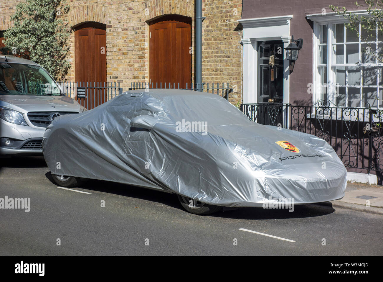 Porsche 911 car under a car cover parked on a road in Notting Hill
