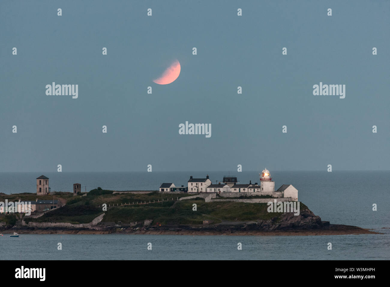 Roches Point, Cork, Ireland. 16th July, 2019. On the 50th anniversary of the Apollo Eleven mission a partial eclipse of a full moon takes place over the Roches Point Lighthouse in Cork Harbour, Ireland. Credit: David Creedon/Alamy Live News Stock Photo