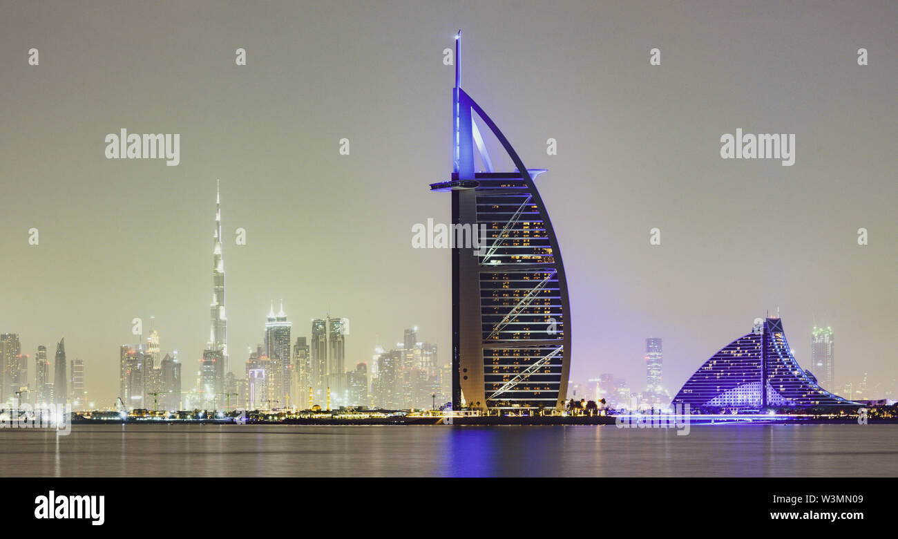 Stunning view of the illuminated Dubai skyline during sunset with the magnificent Burj Khalifa in the background and a luxury hotel in the foreground. Stock Photo