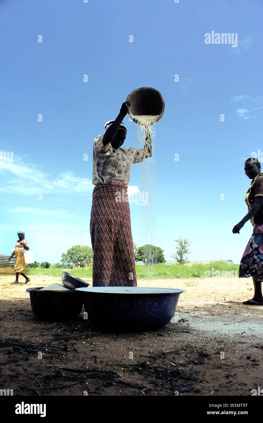 An IDP woman uses a local method to blow-out husks from beans, which is to be sold in market the next day. Although food items are freely distributed to IDPs, some of the items are cheaply sold by IDPs in markets so as to raise funds for their other personal needs. Stock Photo