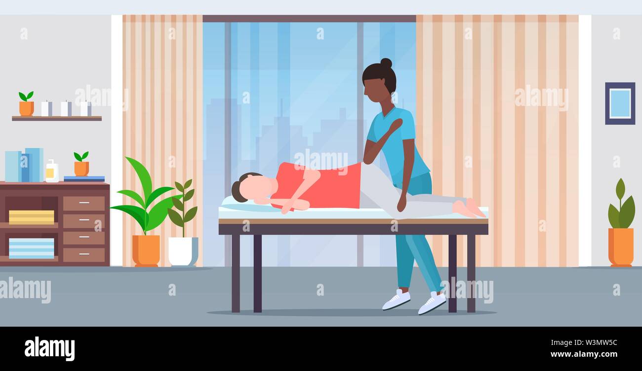 man lying on massage bed african american masseuse therapist doing