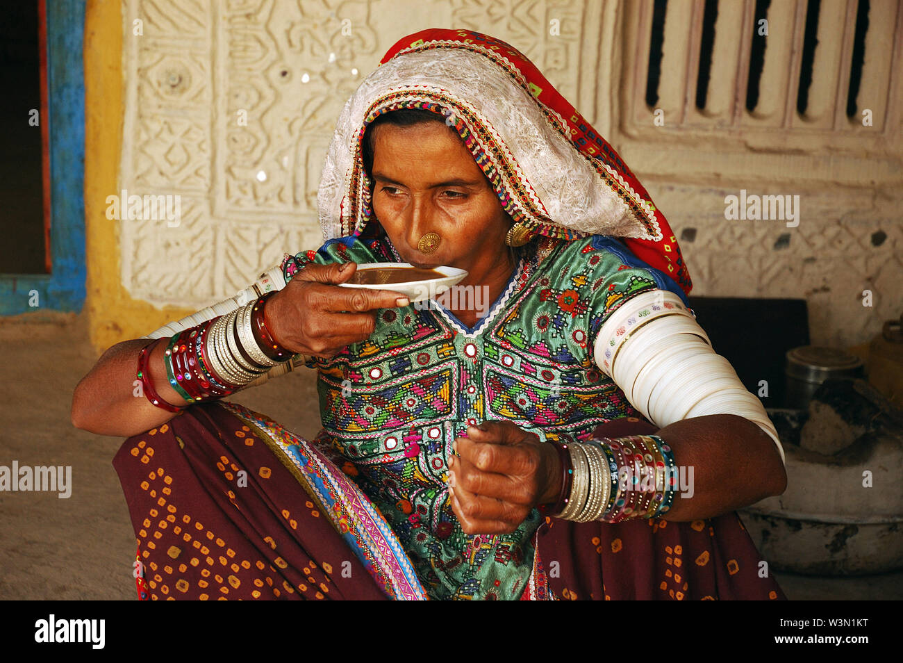 A woman from the ethnic Lambada community having tea at her hut in Bhuj in Gujrat, India. May 24, 2009. Stock Photo