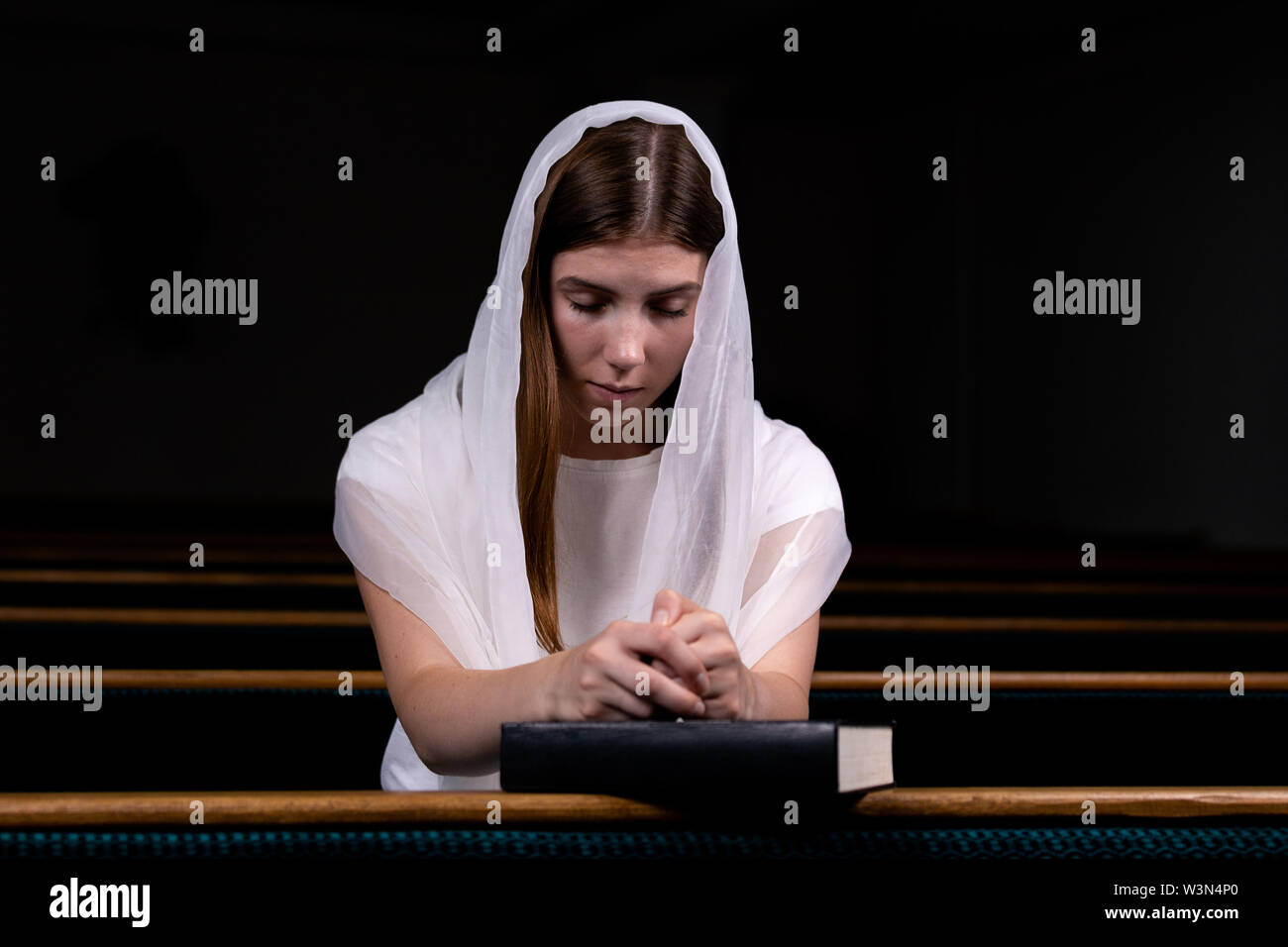 A young modest girl with a handkerchief on her head and a bible in her  hands is sitting in church and praying. The concept of religion, prayer,  worshi Stock Photo - Alamy