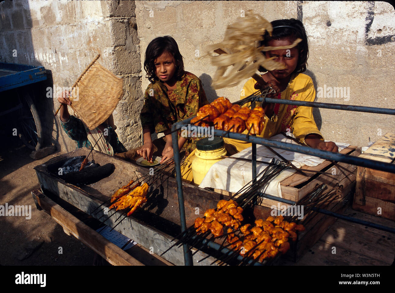 Bengali children selling barbecued meat, in Zia-ul-Haq Colony, a neighborhood where lot of illegal Bengali immigrants live. Karachi. Pakistan. Stock Photo