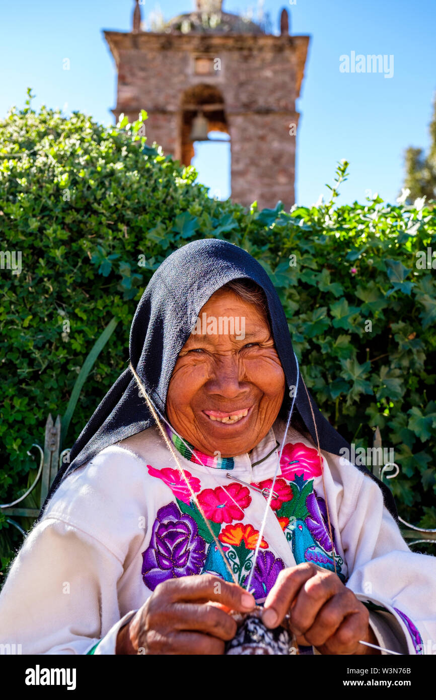 Portrait of elderly indigenous Quechua senior woman wearing traditional Peruvian clothes, knitting, smiling, Amantani Island, Lake Titicaca, Peru Stock Photo