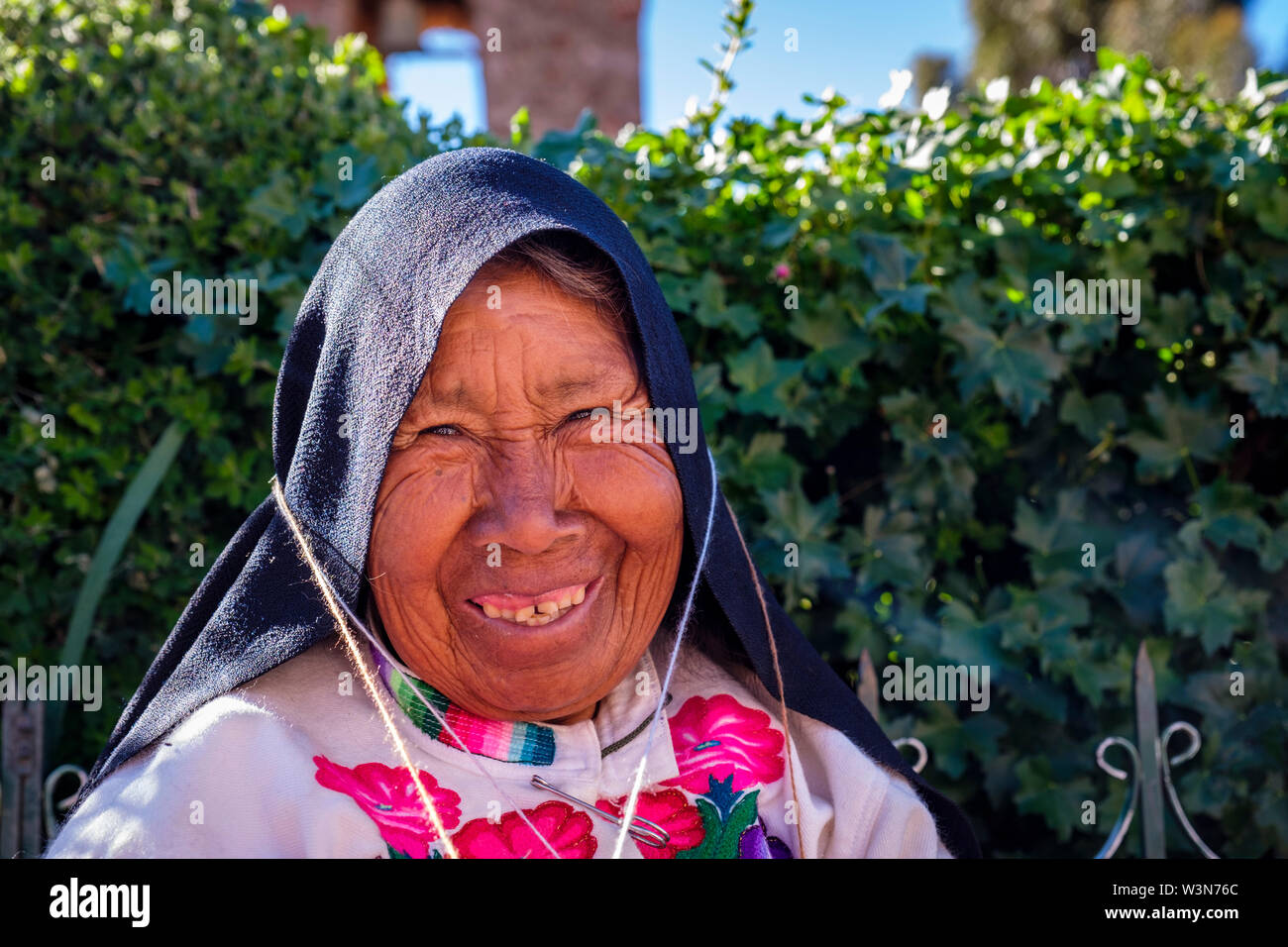 Portrait of elderly indigenous Quechua senior woman wearing traditional Peruvian clothes, knitting, smiling, Amantani Island, Lake Titicaca, Peru Stock Photo