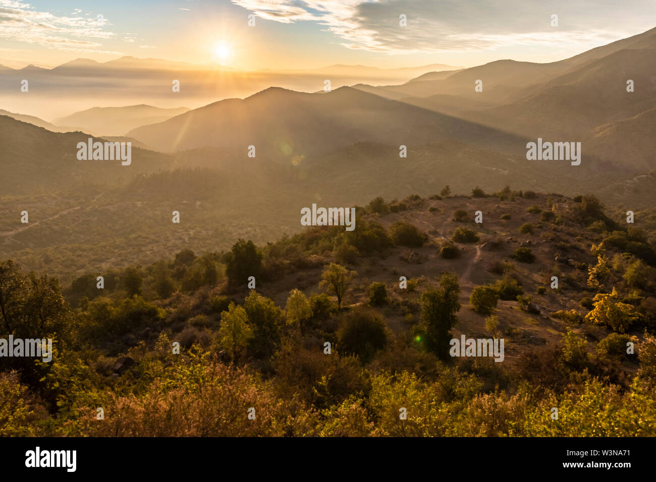 Central Andes valleys sunset view, an idyllic light illuminating the valley slopes full of trees and grass. A rugged landscape on a wild environment i Stock Photo