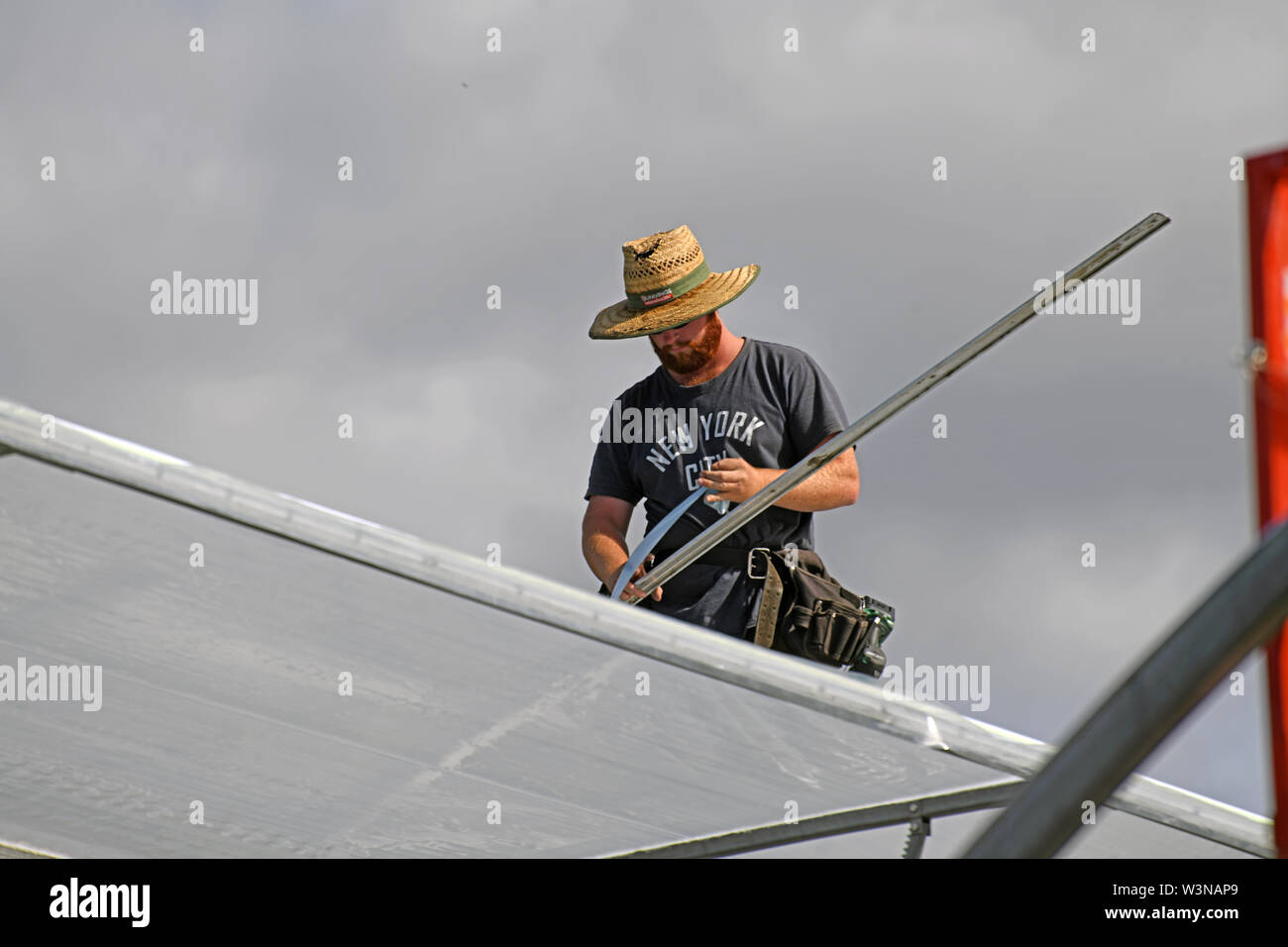 GREYMOUTH, NEW ZEALAND, DECEMBER 12, 2018: Tradesmen secure the plastic on a new tunnel house. Stock Photo