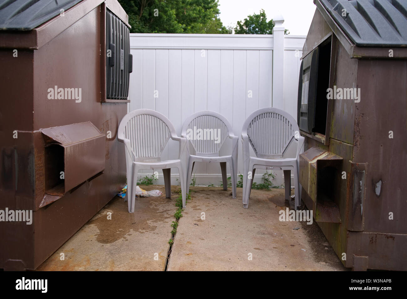 Used lawn chairs dumped by a dumpster instead of the recycling bin