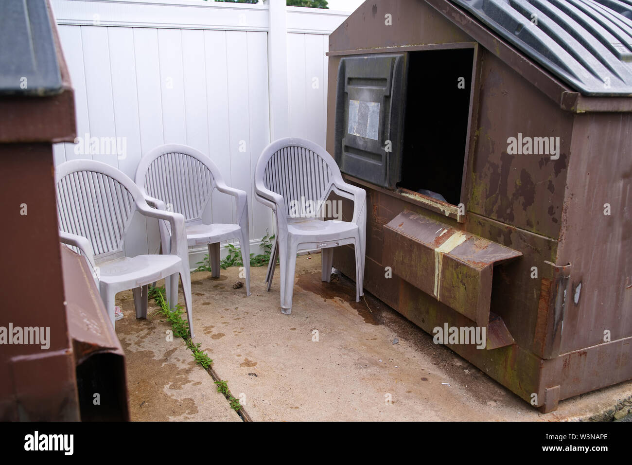Used lawn chairs dumped by a dumpster instead of the recycling bin
