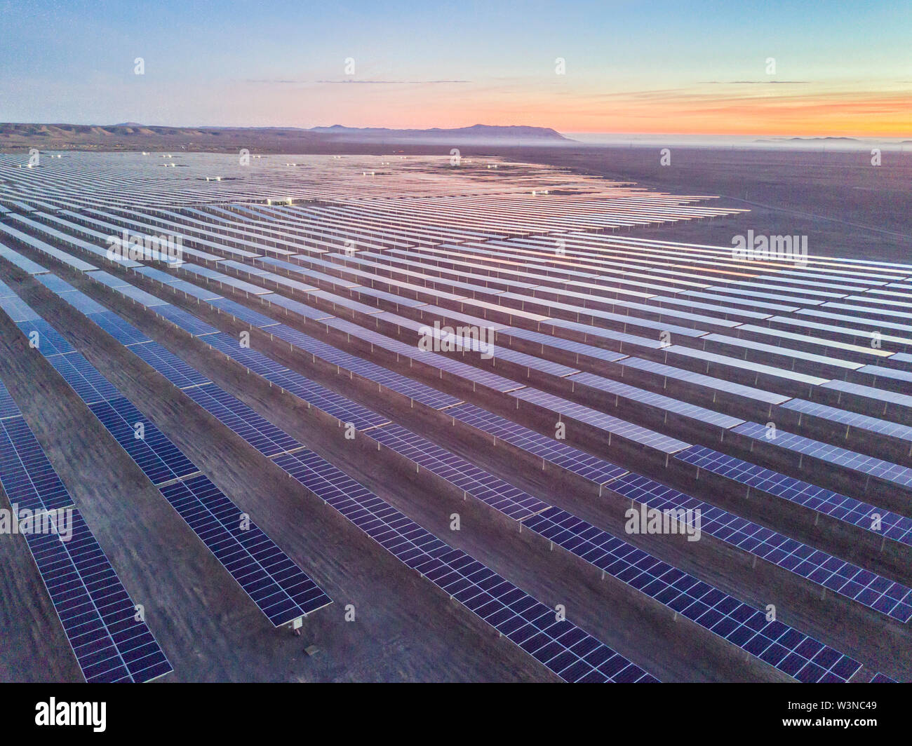 Aerial view of hundreds solar energy modules or panels rows along the dry lands at Atacama Desert, Chile. Huge Photovoltaic PV Plant in an arid scene Stock Photo
