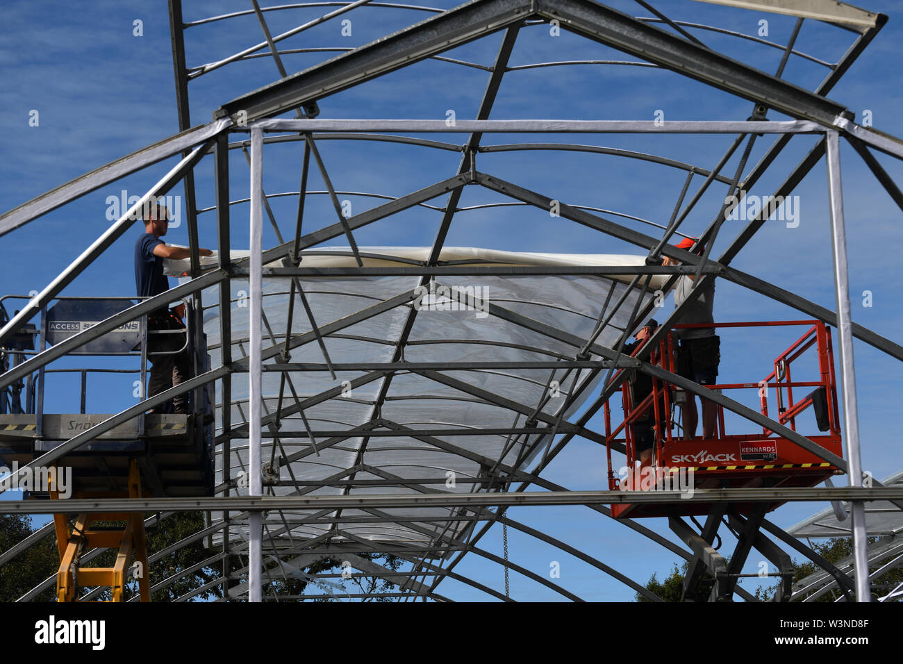 GREYMOUTH, NEW ZEALAND, DECEMBER 12, 2018: Tradesmen secure the plastic on a new tunnel house. Stock Photo