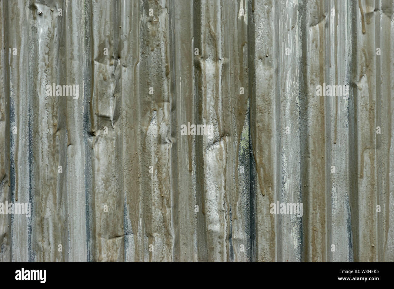 The corrugated metal surface of grey color with runs of old paint. Texture or background for a project Stock Photo
