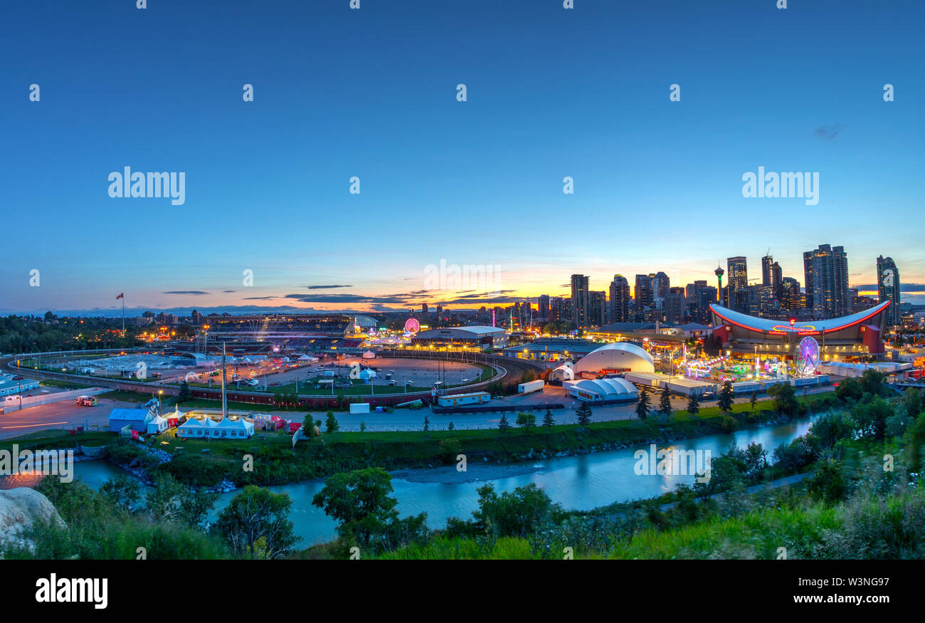 CALGARY, CANADA - JULY 14, 2019: Panorama of golden sunset over the Calgary Stampede fairgrounds surrounded by the Bow River with the city's urban sky Stock Photo
