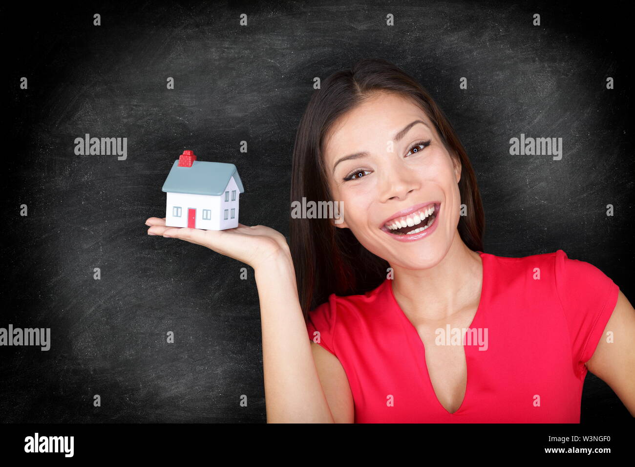 New house owner woman happy - blackboard concept. Woman showing mini house model. Stock Photo