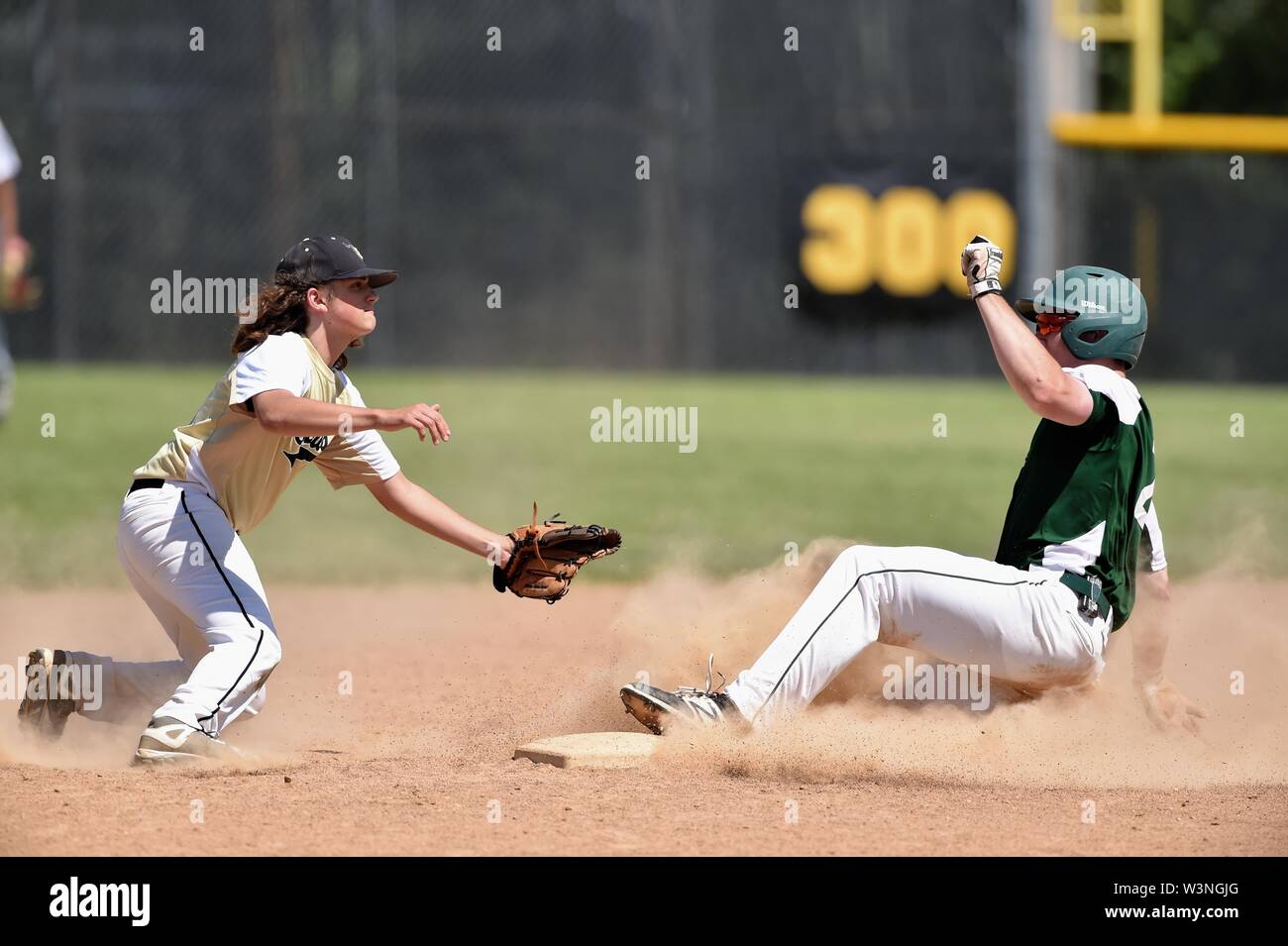 Runner sliding safely into second base with a steal as an infielder took a late throw from behind the bag. USA. Stock Photo
