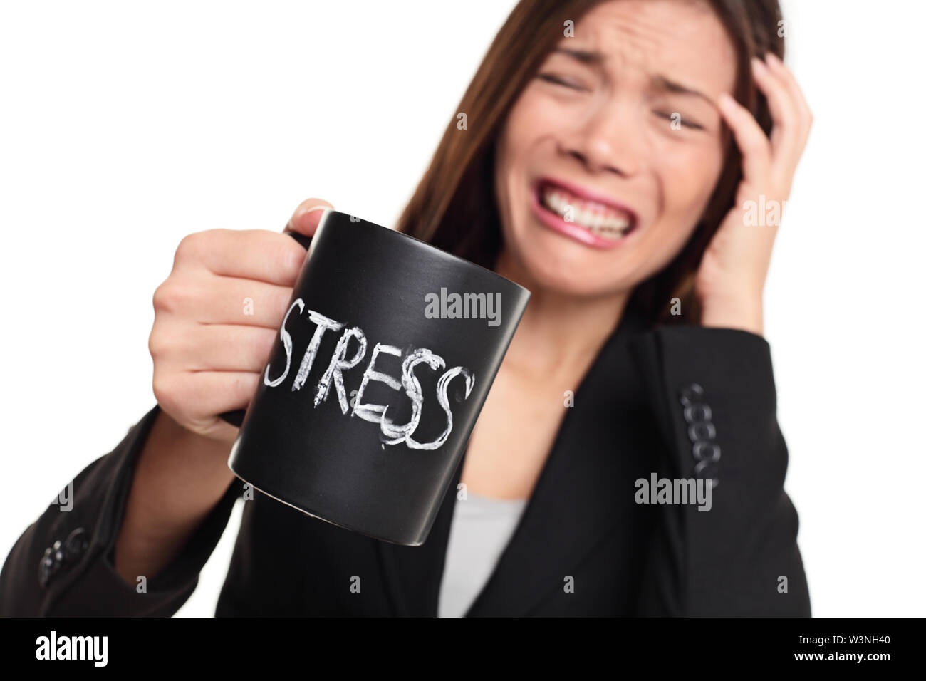 Stress at work concept. Business woman stressed being to busy. Businesswoman in suit holding head drinking coffee creating more stress. Mixed race Asian Caucasian female isolated on white background. Stock Photo