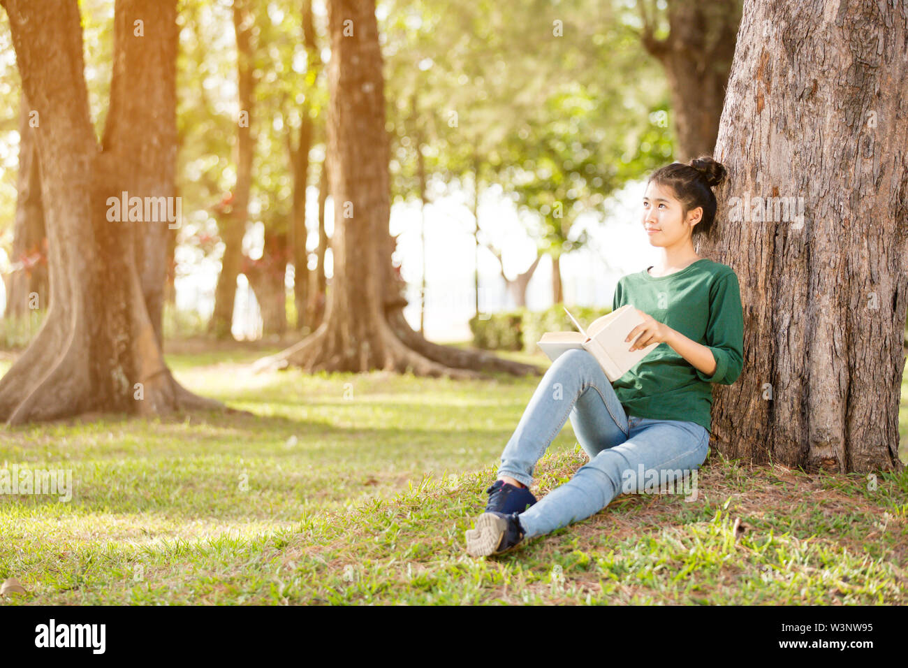 Beautiful young asian woman sitting and reading book in a park Stock ...