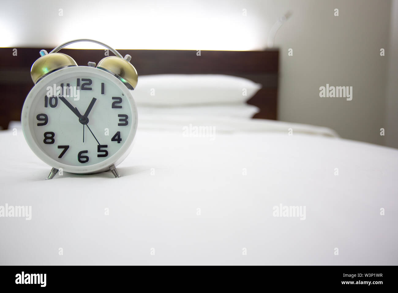white alarm clock and bed Stock Photo Alamy