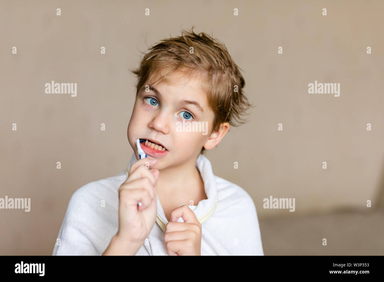 A Cute Little Blonde Boy With Blue Eyes Brushing His Teeth With A