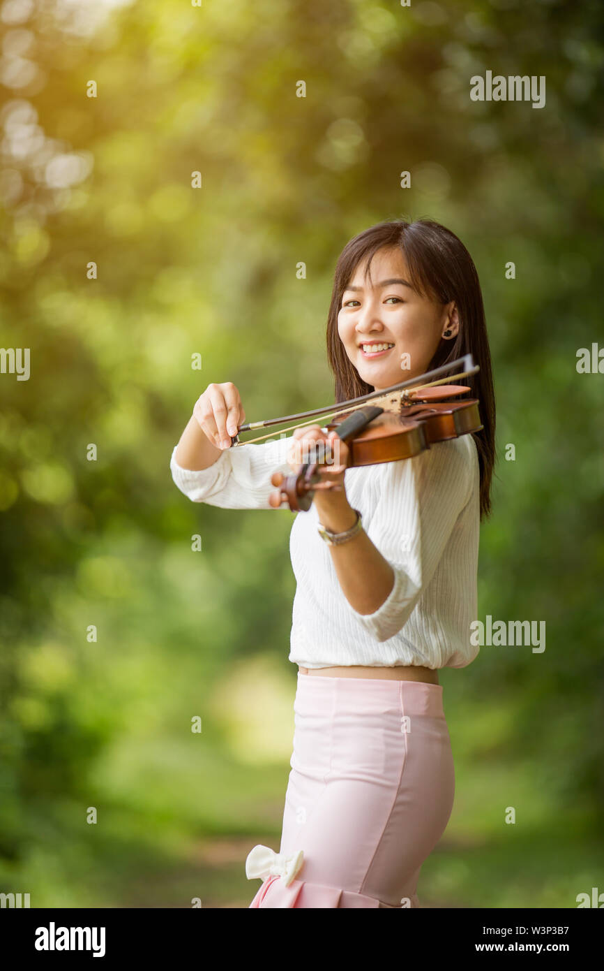 asia woman playing violin in garden with sunshine Stock Photo - Alamy