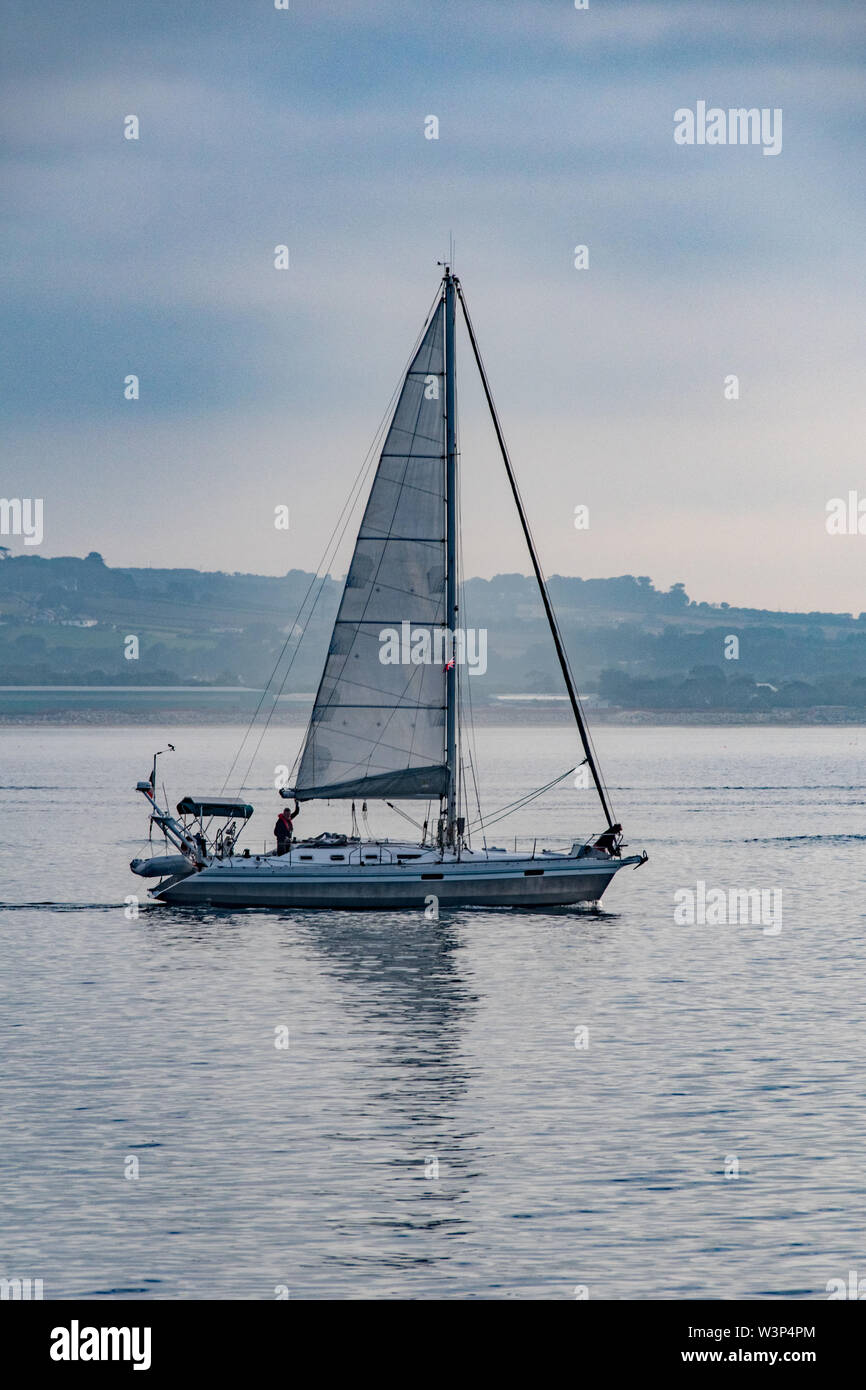 Newlyn, Cornwall, UK. 17th July 2019. UK Weather.  Warm and sunny but not much wind for this sailing boat leaving it's overnight mooring at Newlyn.  Credit Simon Maycock / Alamy Live News. Stock Photo
