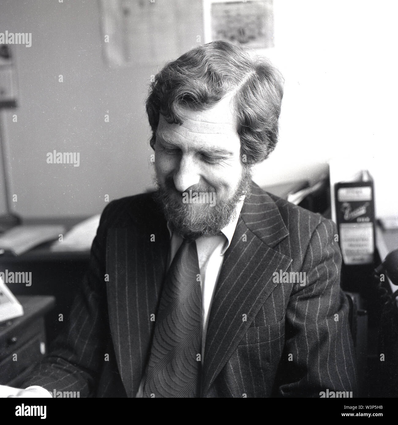 1970s, historical, a bearded man in an office wearing a suit of the era, a pinstripe with wide lapels and a shirt and 'kipper' tie. Stock Photo