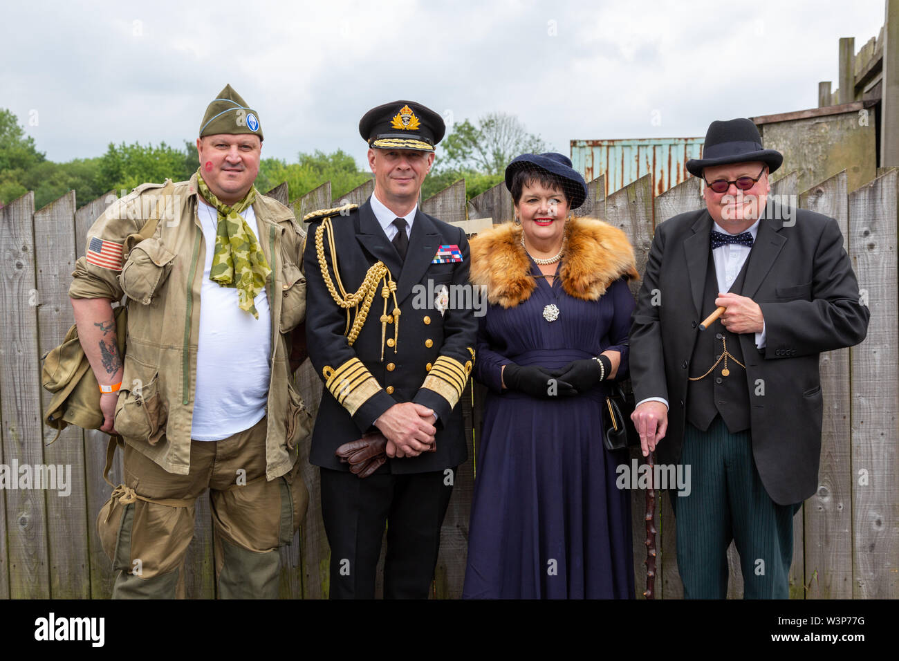 Four people dressed in wartime fashion, with two lookalikes, Winston Churchill and HM King Stock Photo