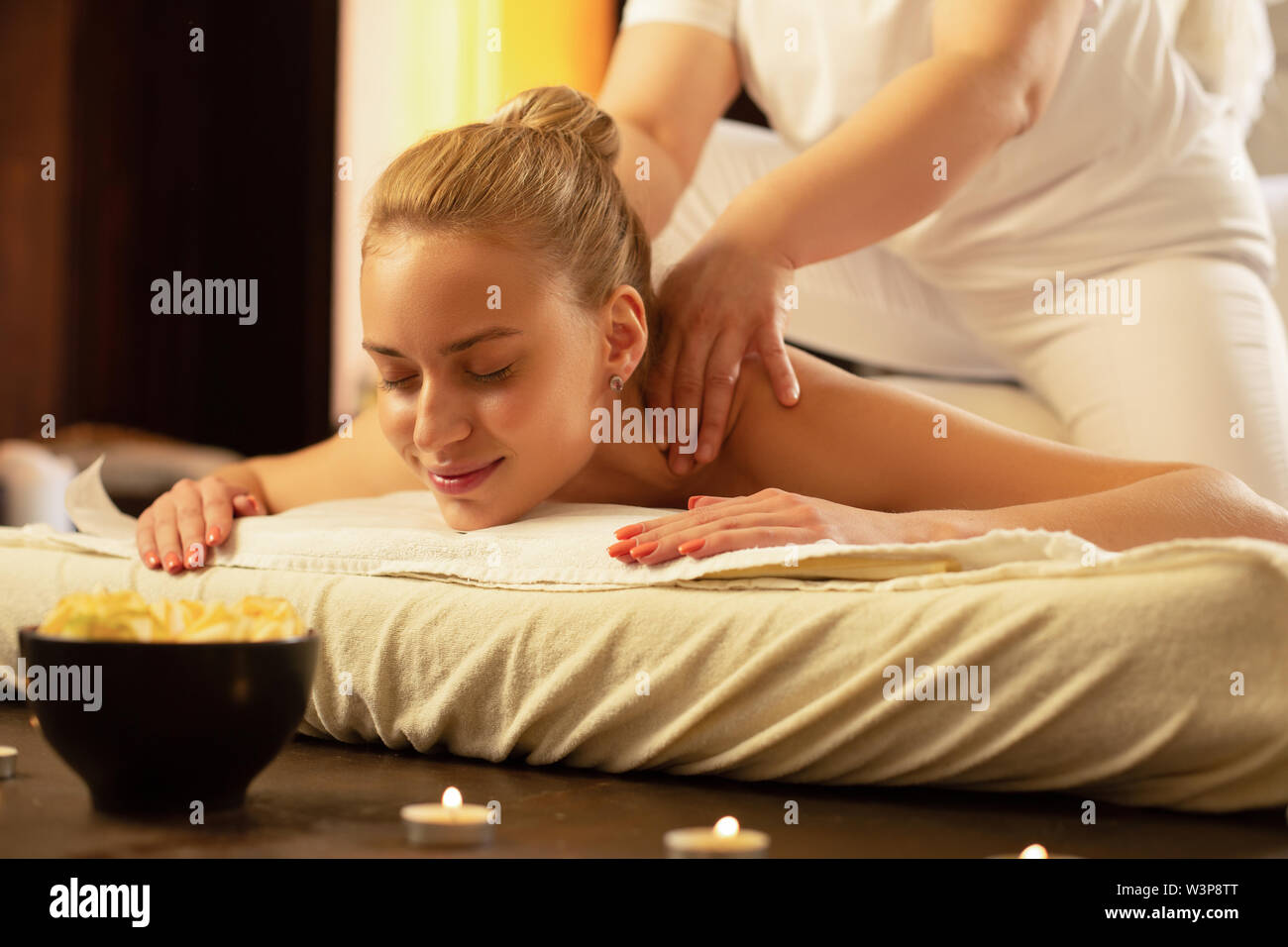 Massage session. Smiling blonde woman with tied hair being satisfied with  skills of massage master in salon Stock Photo - Alamy