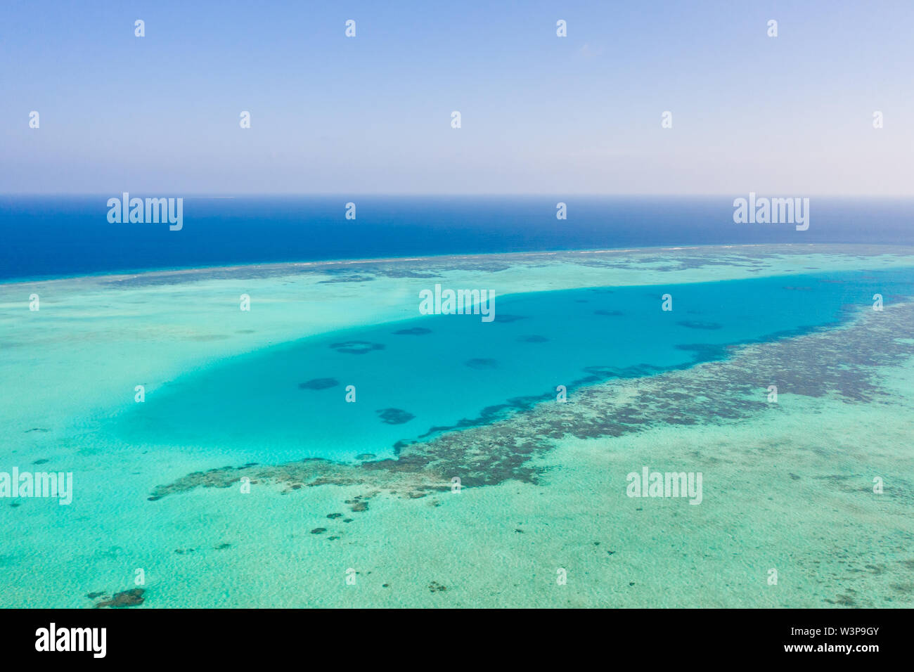 Atoll and blue sea, view from above. Seascape by day. Turquoise and blue sea water. Stock Photo