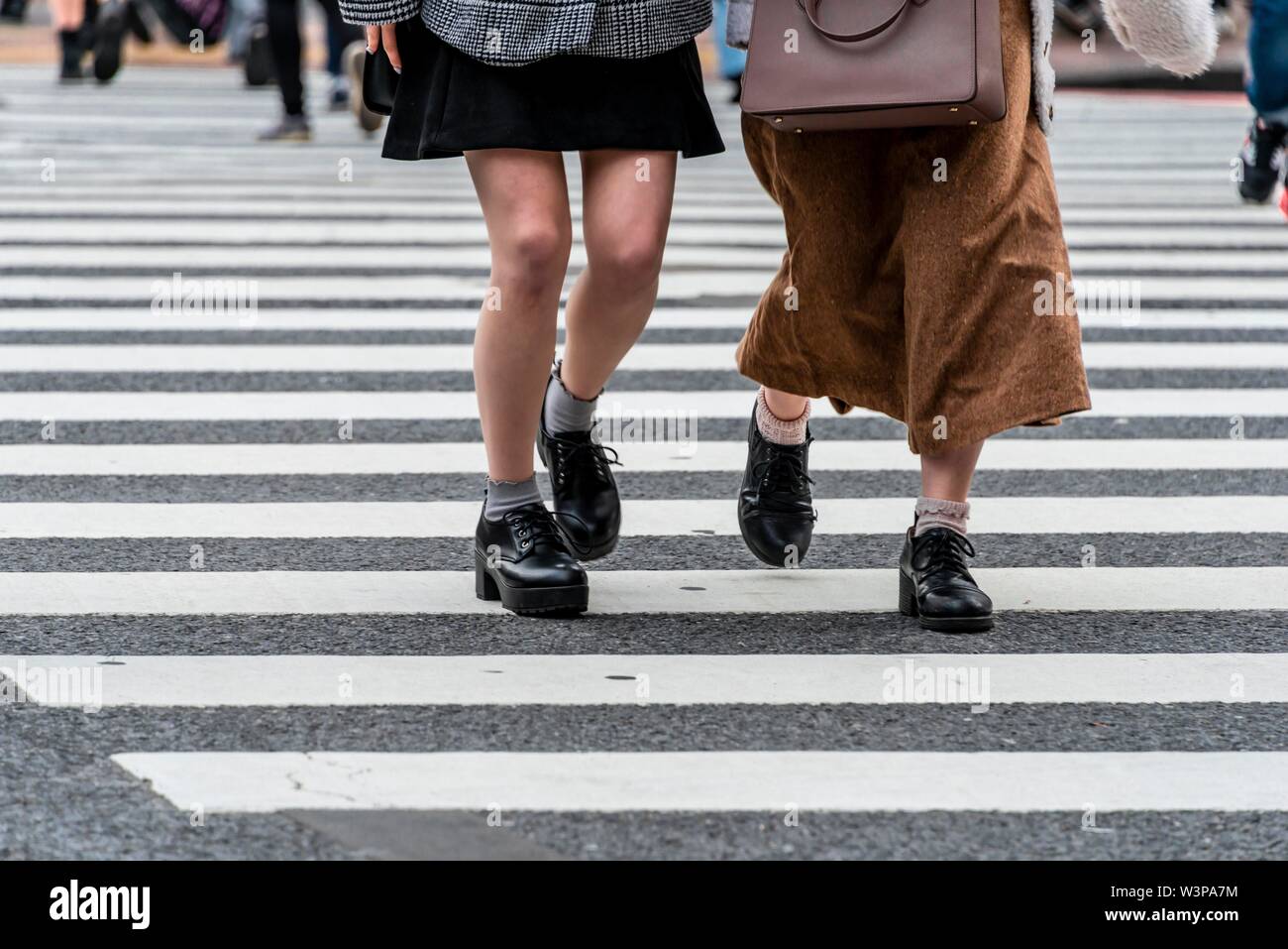 Two pedestrians crossing zebra crossing, close-up, Shibuya Crossing, Shibuya, Udagawacho, Tokyo, Japan Stock Photo