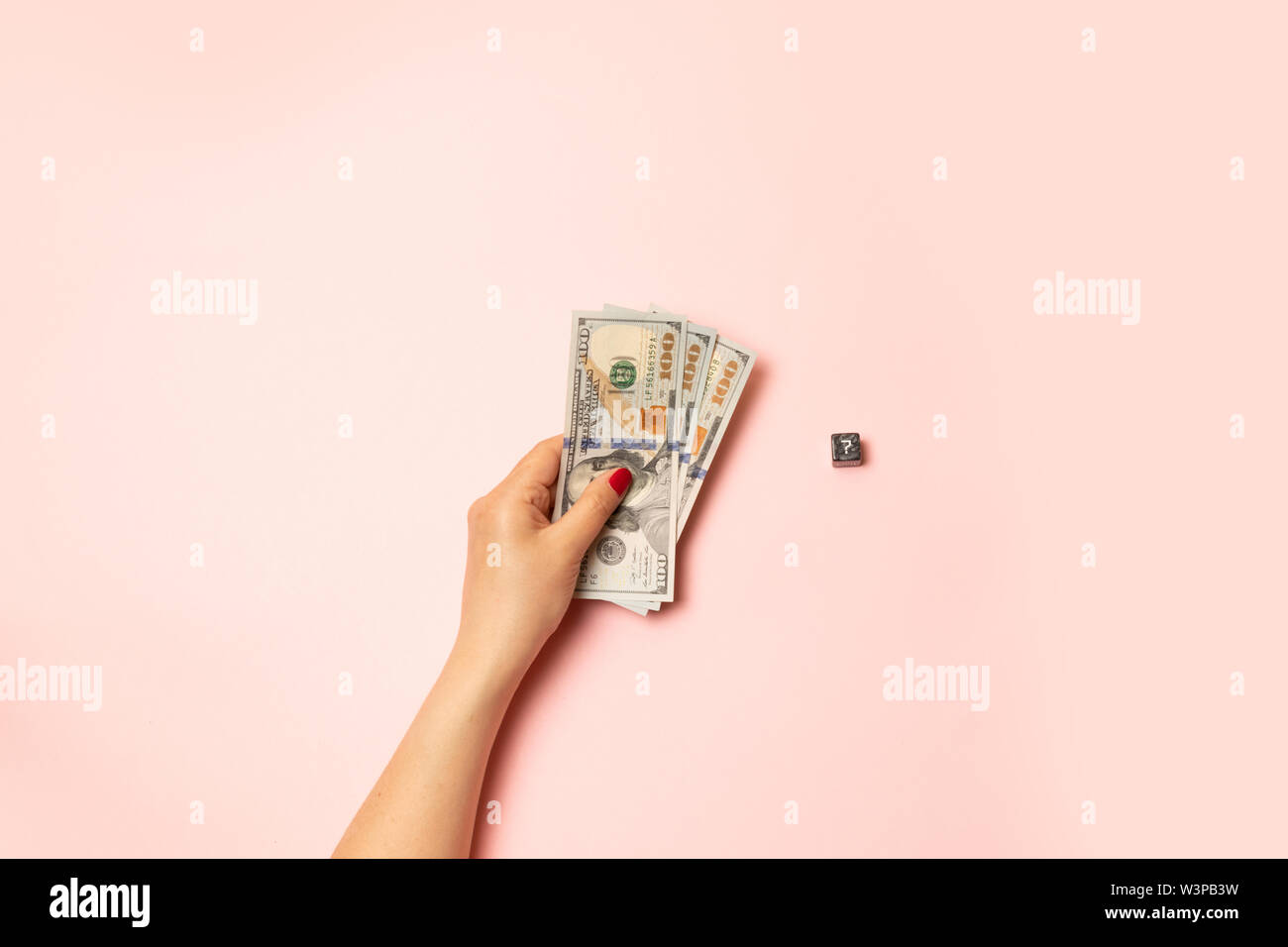 Female hand with a red manicure holding money dollar bills on a pink ...