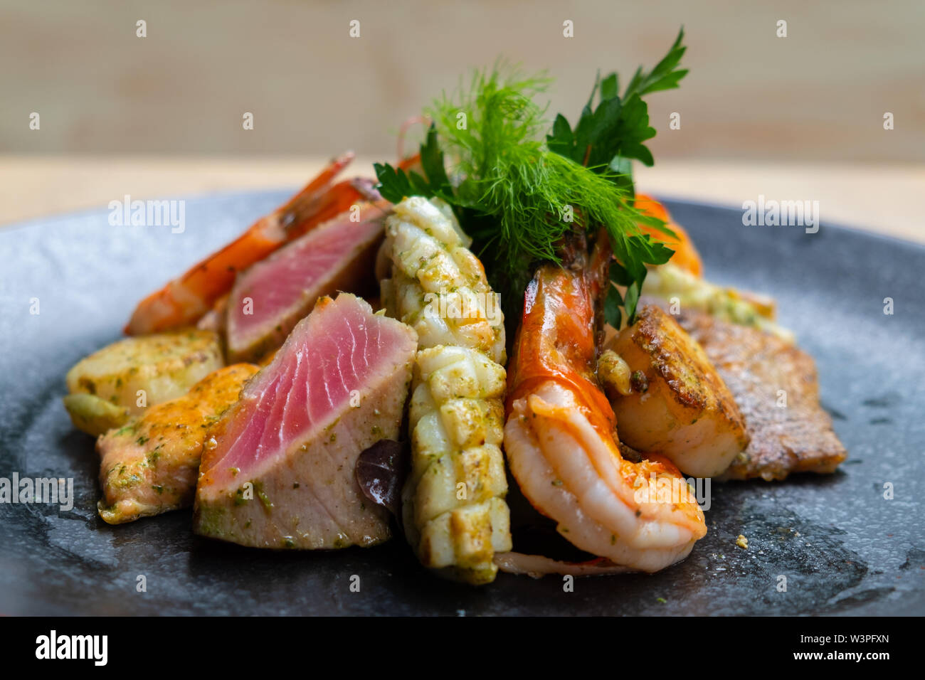 close up of mix grilled seafood and fish platter with fresh salad, prawns, scallop, tuna, salmon