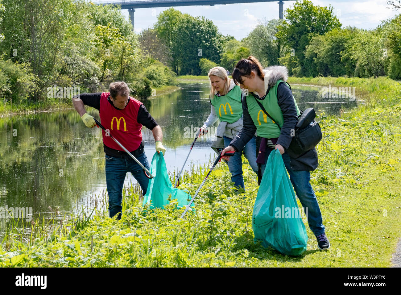 Volunteers picking up litter along canal bank Stock Photo