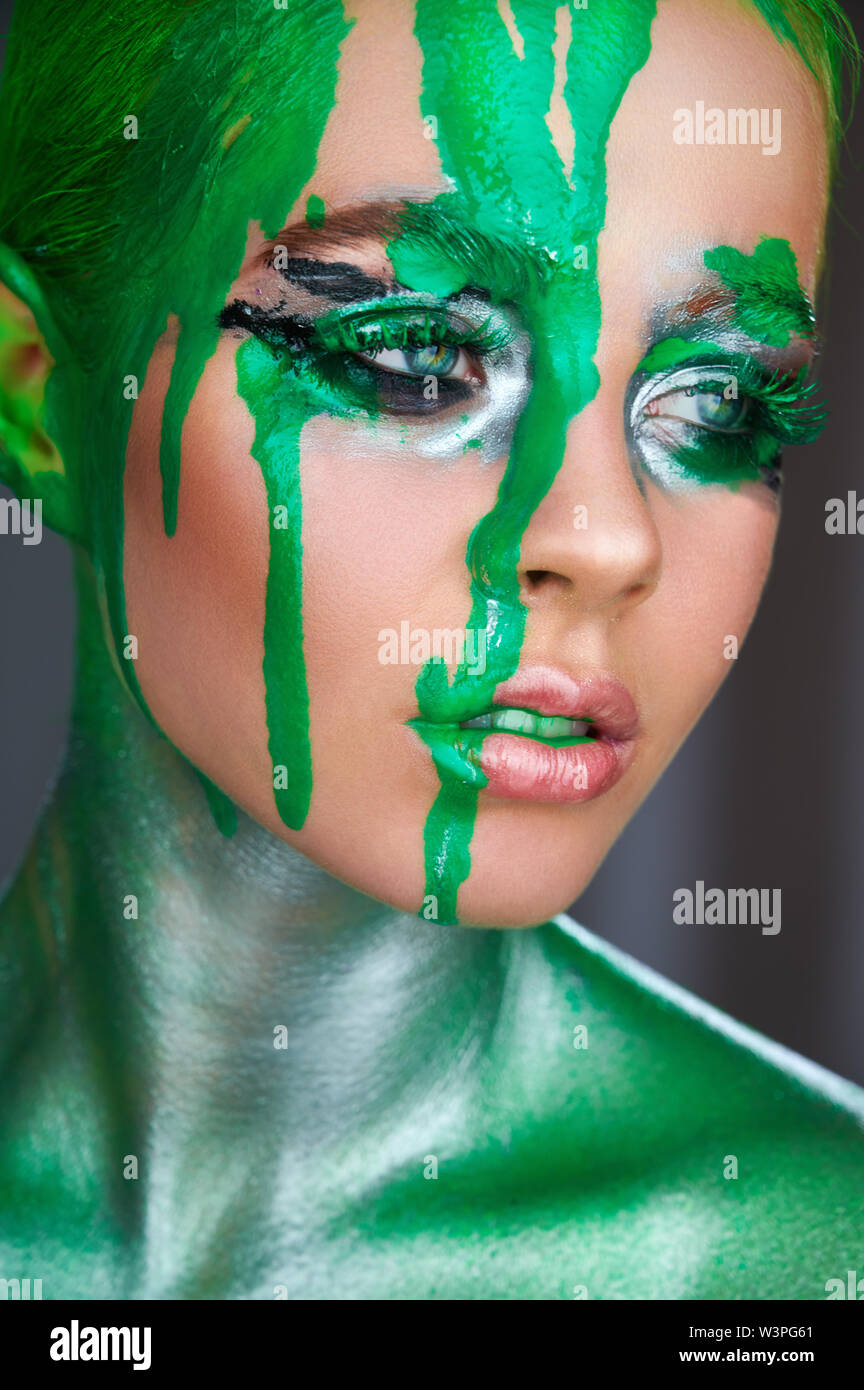 High fashion model. An amazing woman with green metallic makeup and leaking green neon paint. Glitter vivid makeup Stock Photo