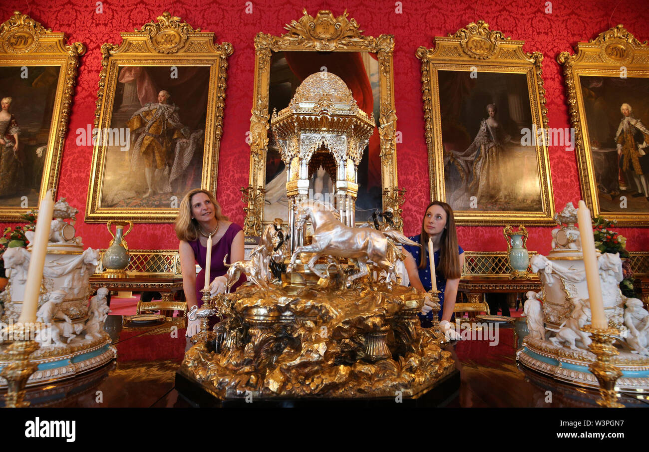 A pair of Royal Collection employees adjust placings at a recreation of a Victorian dinner in the State Dining Room featuring the Alhambra fountain (centre) at the exhibition to mark the 200th anniversary of the birth of Queen Victoria for the Summer Opening of Buckingham Palace, London. Stock Photo