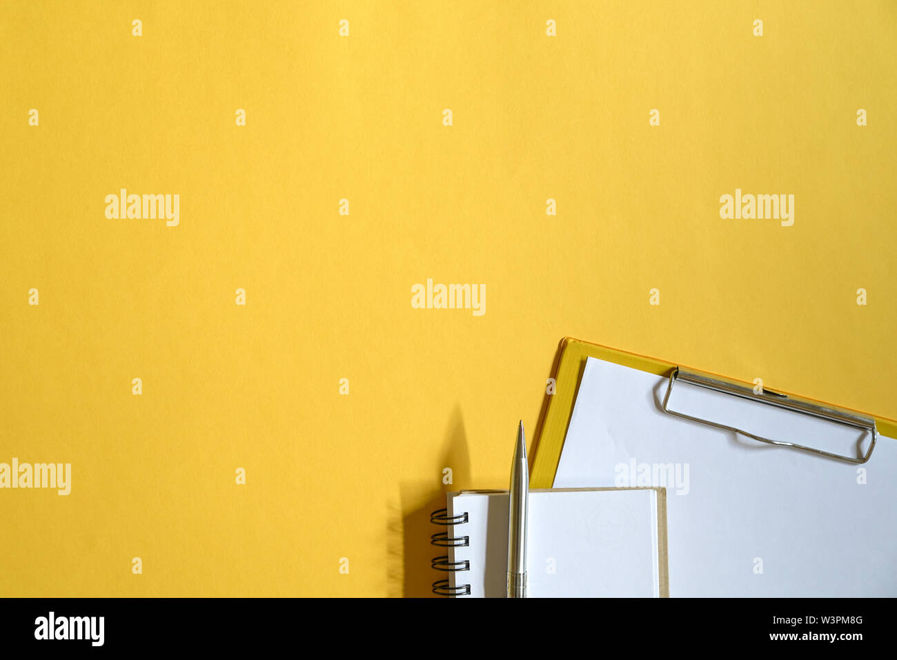 Yellow color office table top view with clipboards with paper, memo pad
